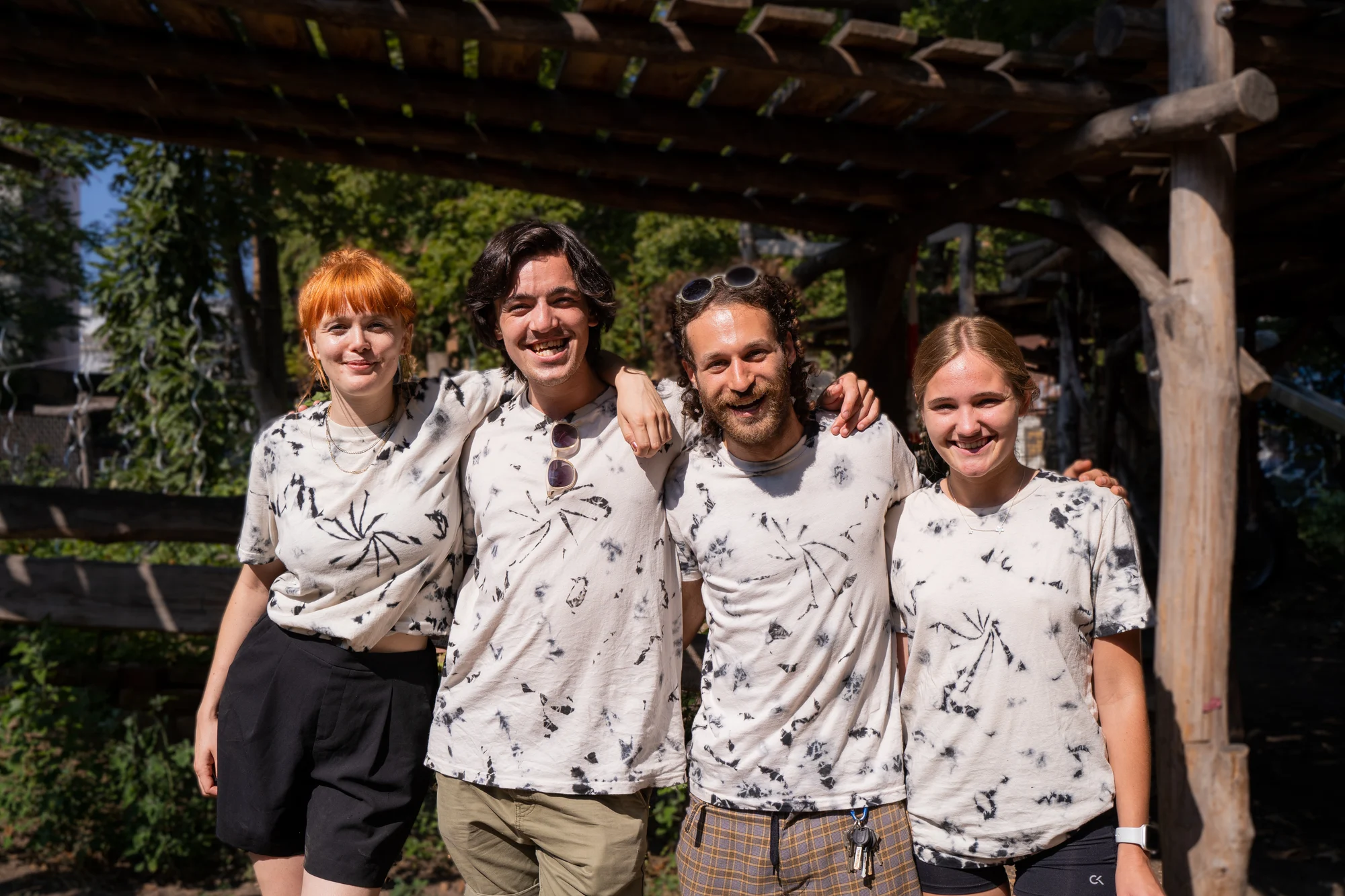 Vier LevelUp-Trainer:innen stehen Arm in Arm beieinander und lachen in die Kamera