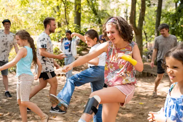 Gruppe von Jugendlichen und Trainer:innen in Bewegung bei einem Aufwärmspiel im Freien