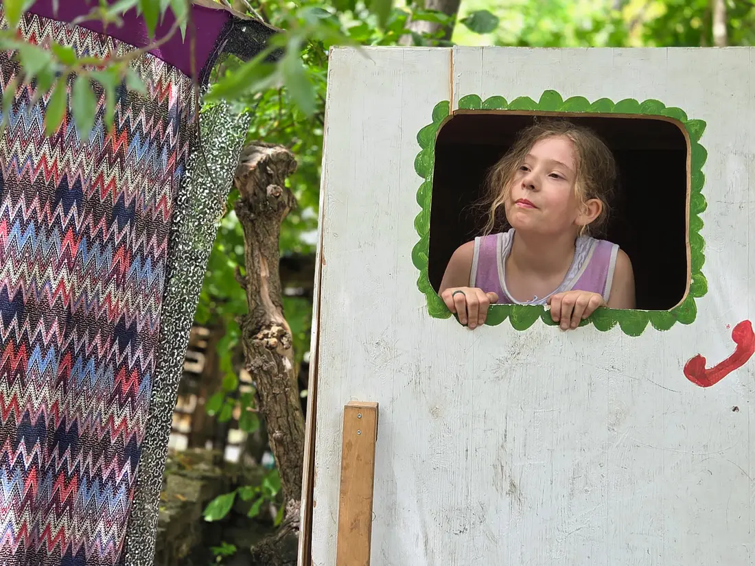 Ein Kind schaut aus dem Fenster einer selbst gebauten Theaterkulisse im LevelUp-Camp