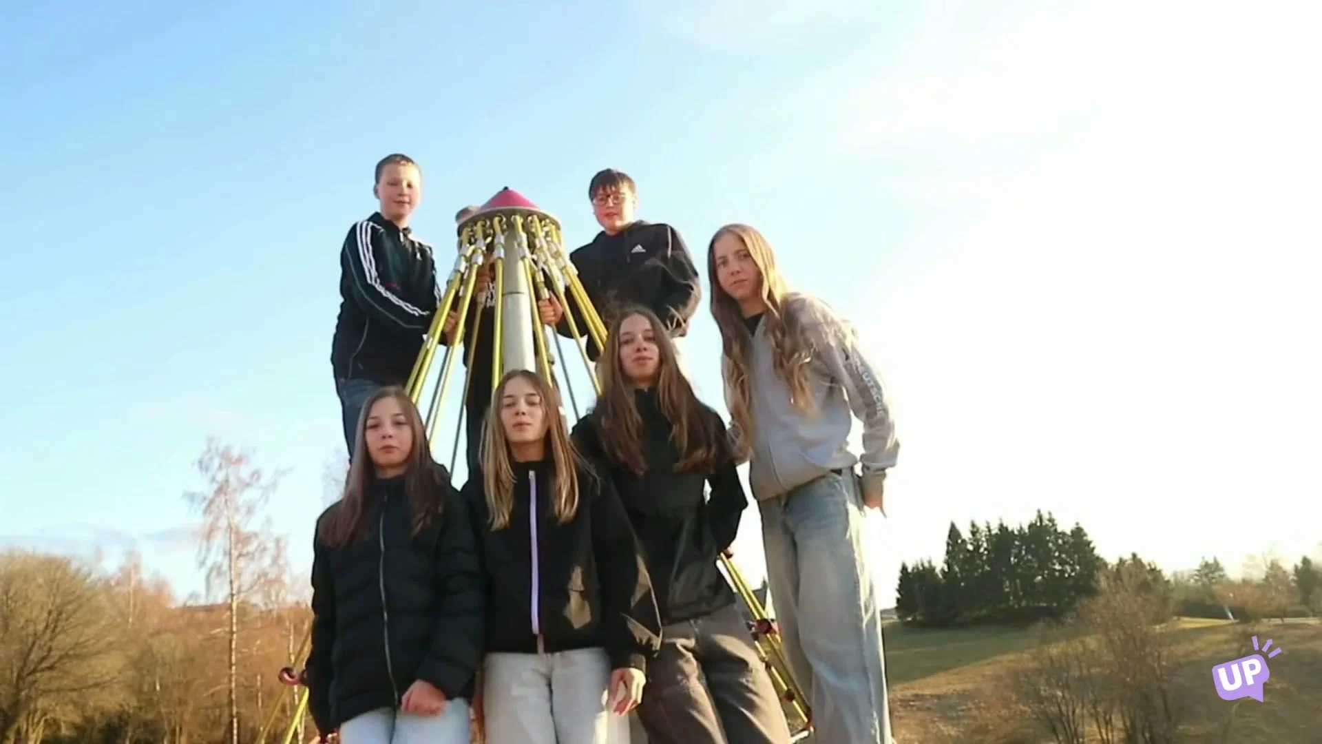 A class posing together on a climbing frame in the evening light on an English class camp