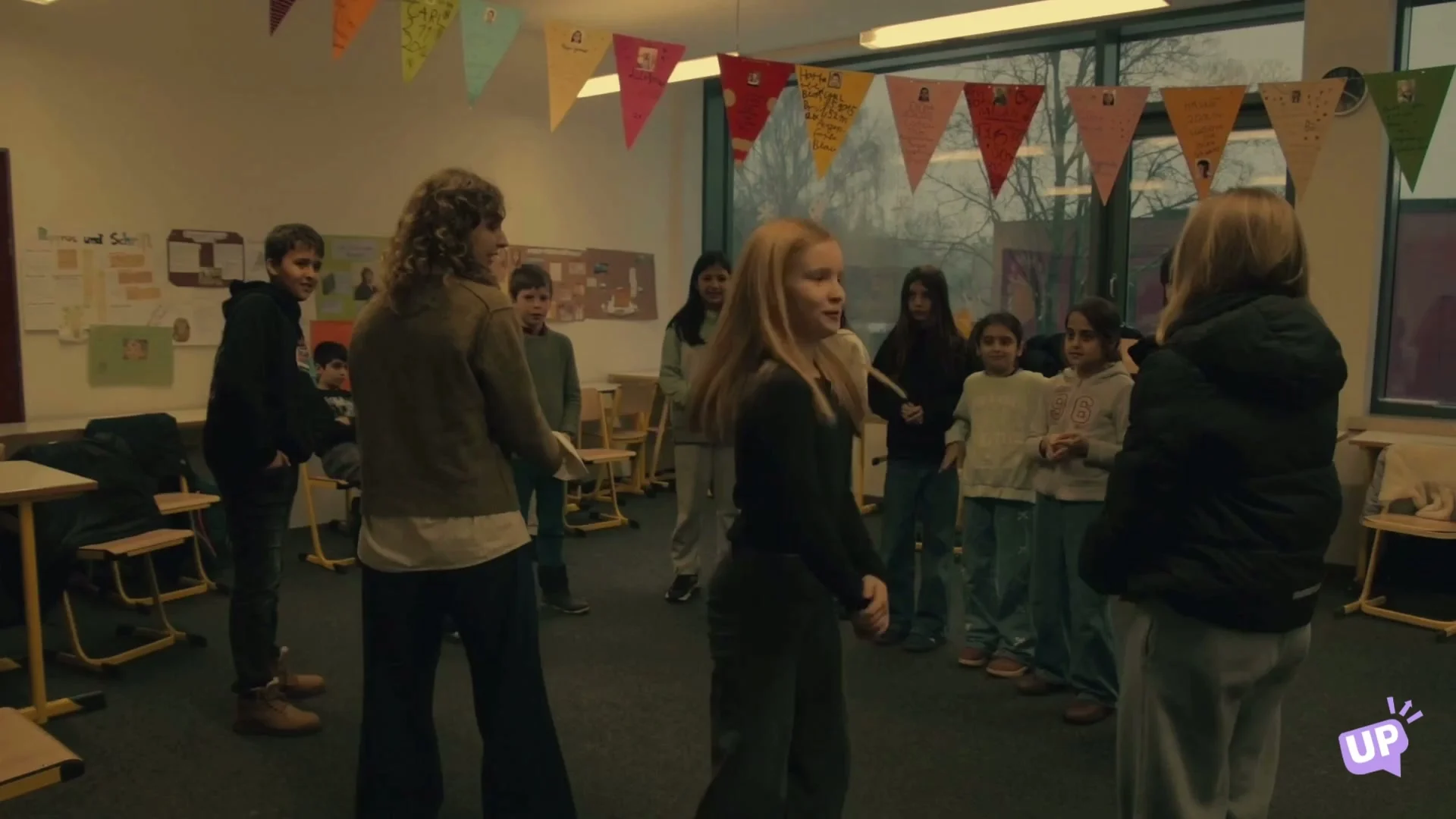 A class standing in a circle for an English drama game in their decorated classroom