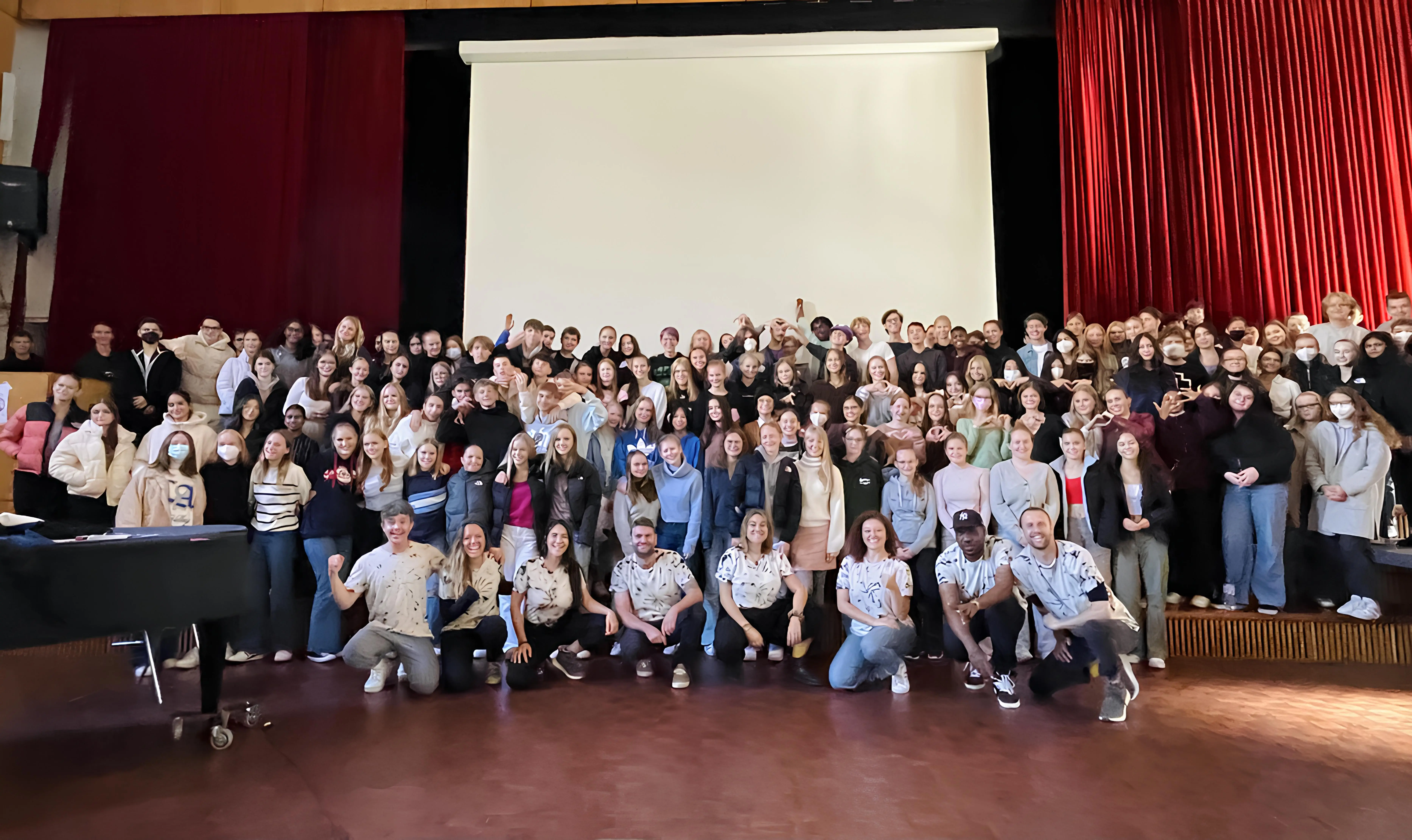 A whole school with the LevelUp team on stage in front of a red curtain after the final showcase